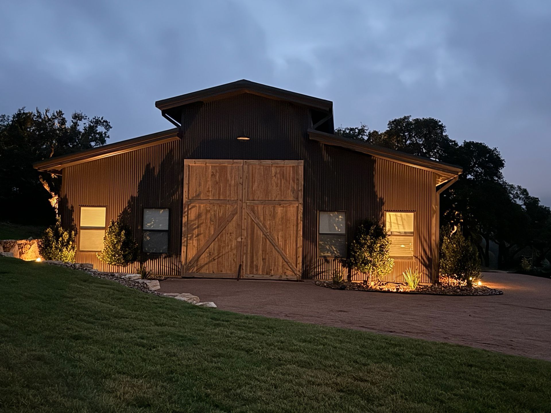 A large wooden barn is lit up at night.
