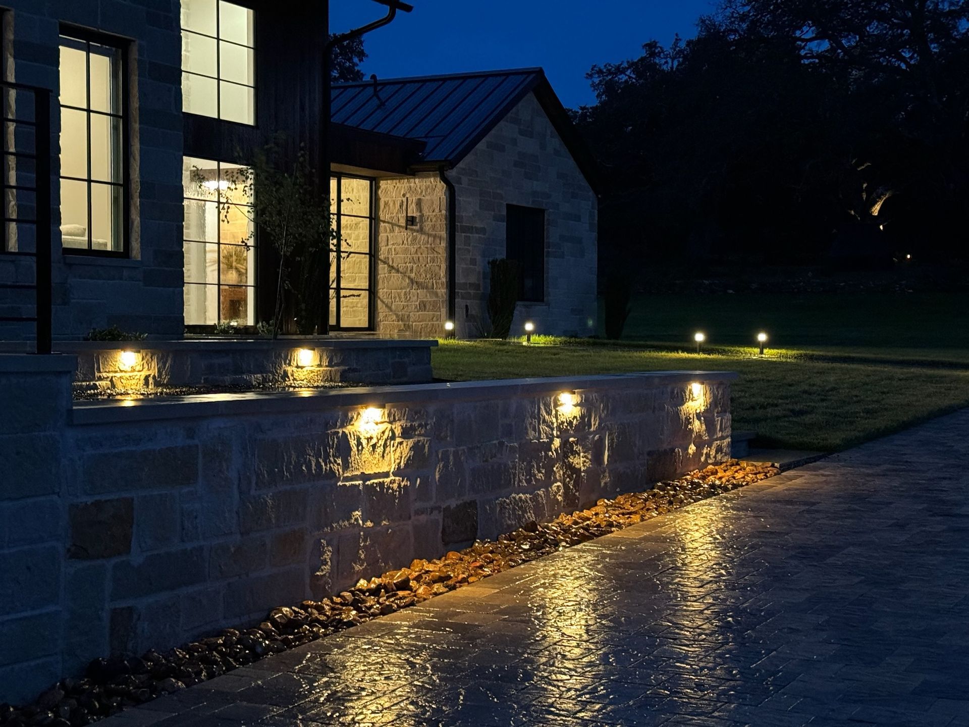 A house is lit up at night with lights on the sidewalk