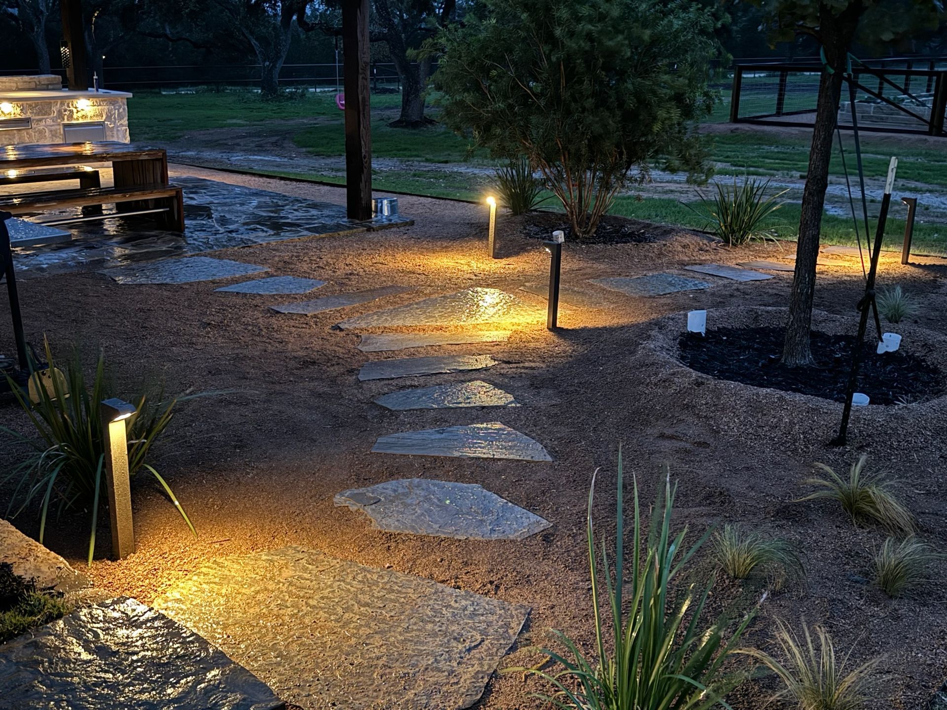 A stone walkway is lit up at night in a park.