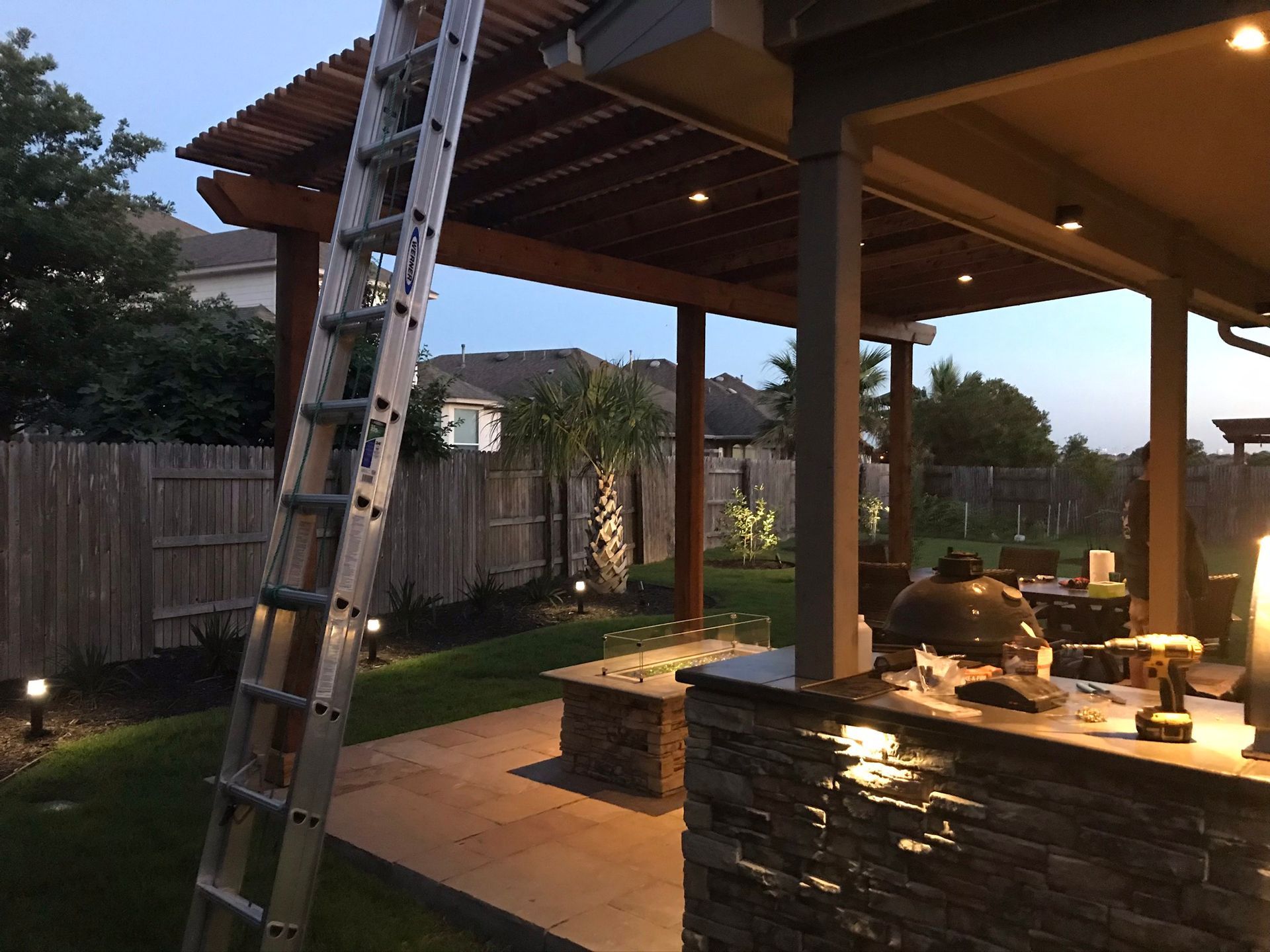 A ladder is sitting under a pergola in a backyard