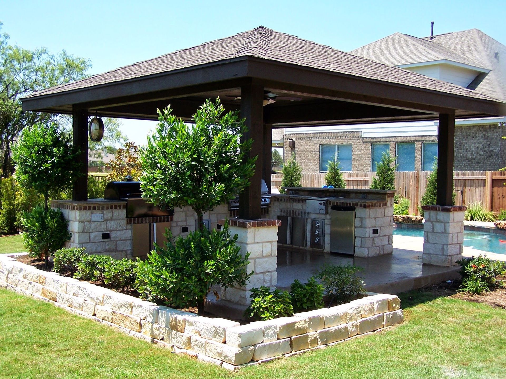A gazebo with a kitchen in the backyard of a house