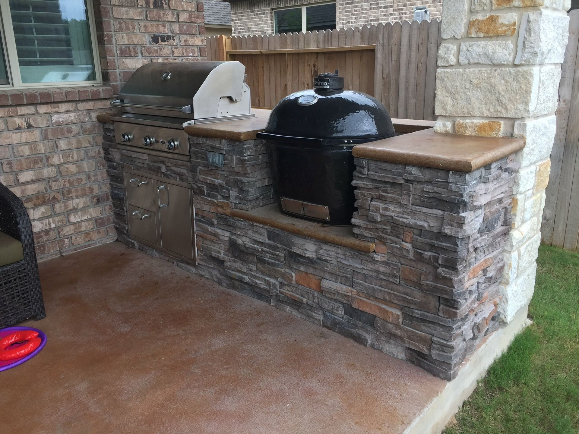 A grill is built into a stone wall on a patio.