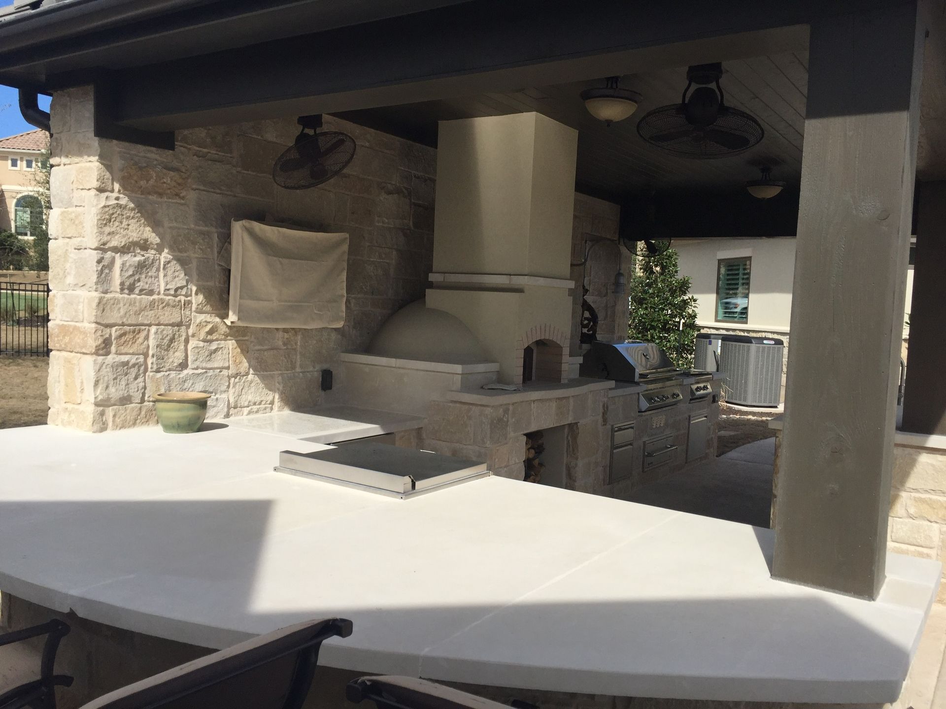 An outdoor kitchen with a pizza oven and a table and chairs.