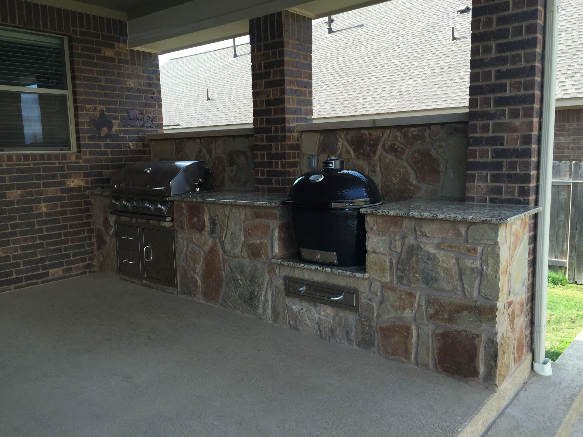A patio with a grill and a brick wall.