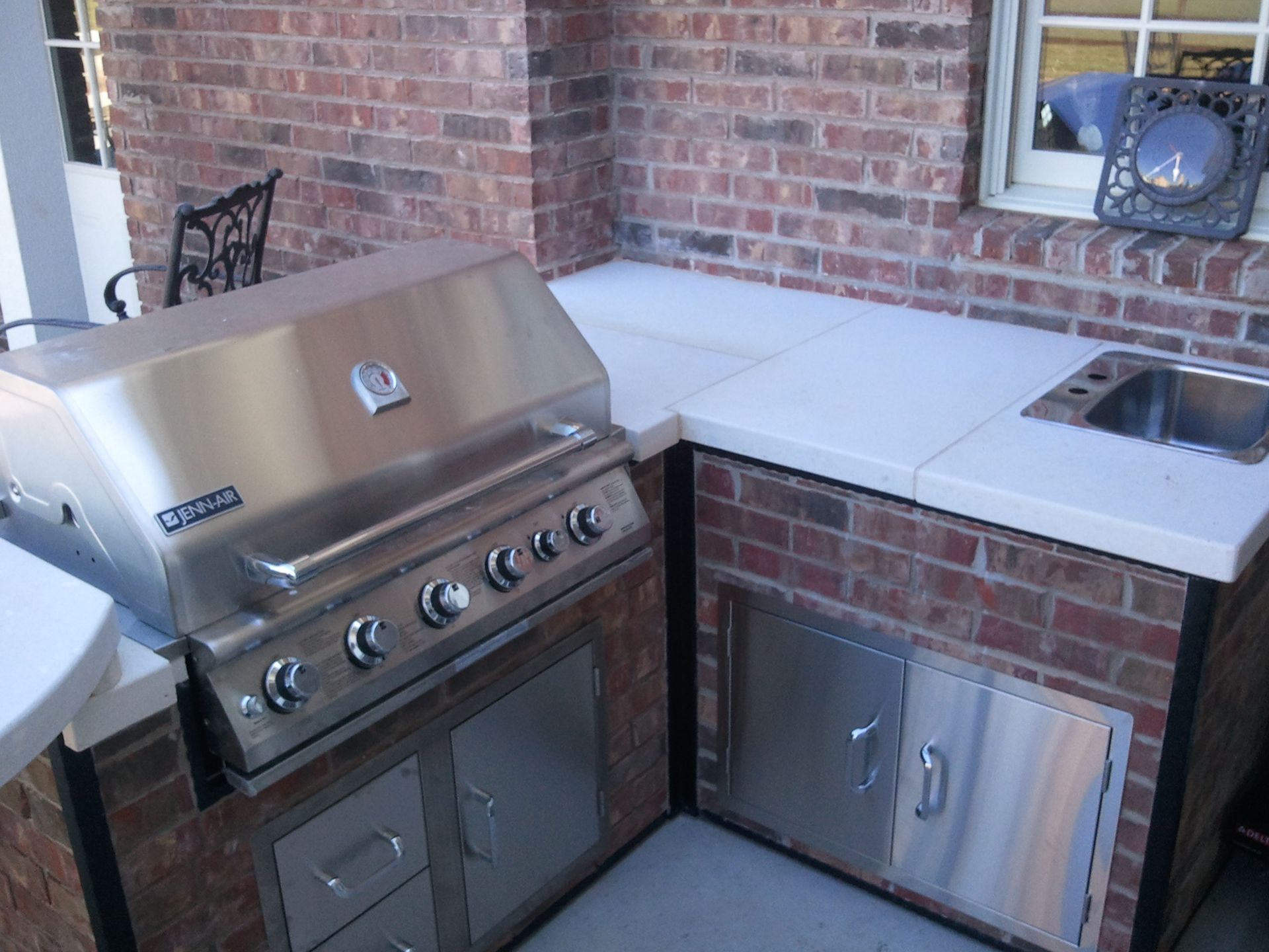 A stainless steel grill is sitting in front of a brick wall