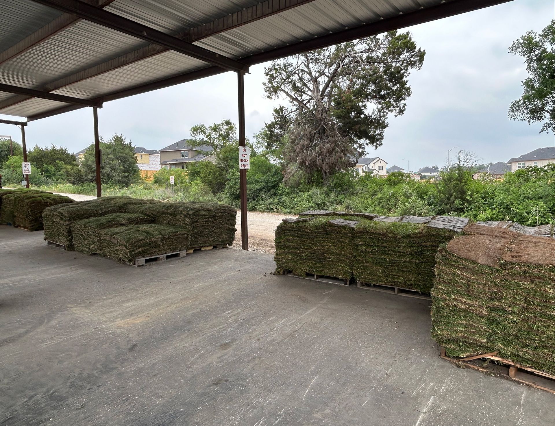 A bunch of bales of hay are sitting under a roof