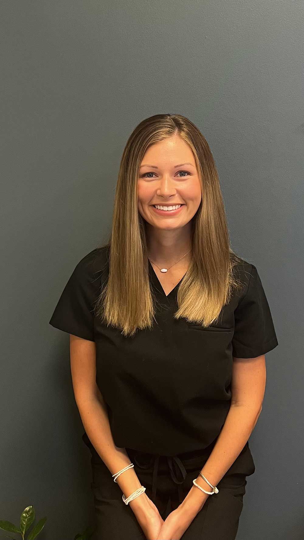 A woman in a black scrub top is smiling for the camera.