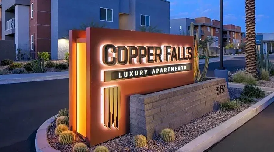 Copper Falls luxury apartment sign illuminated at dusk outside apartment buildings