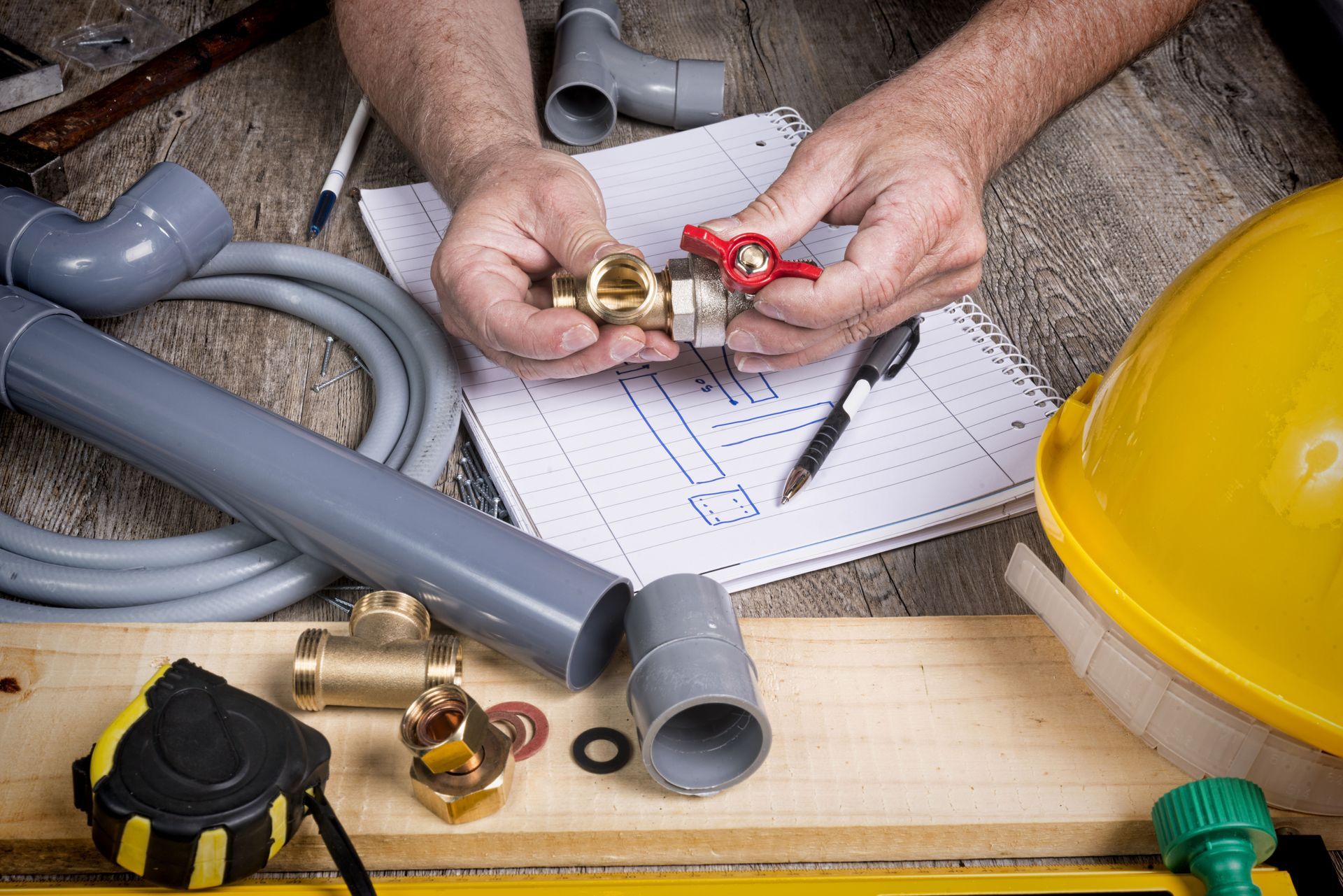 A plumber is working on a pipe on a wooden table.