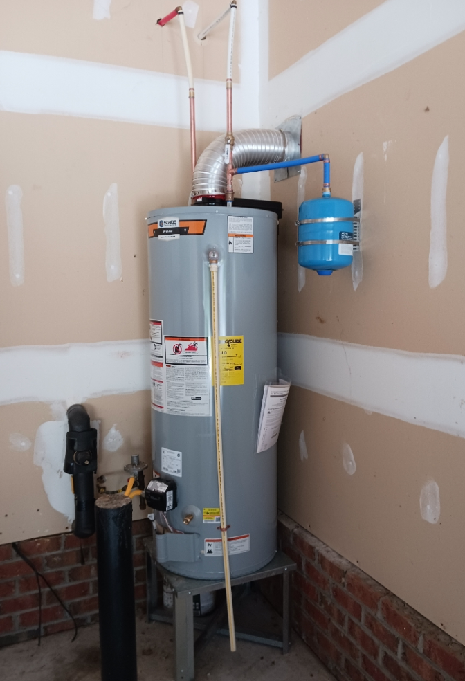 A water heater is sitting in a room next to a brick wall