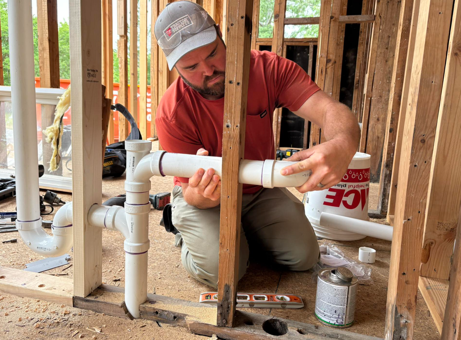 A man is working on a pipe in a building under construction.
