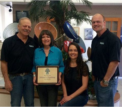 A group of people are posing for a picture and one of them is holding a framed certificate that says johnson 's painting
