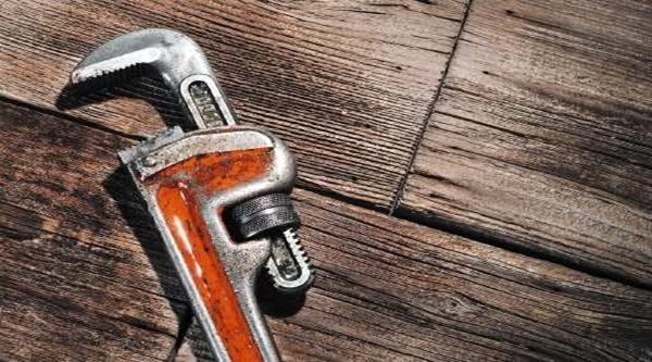 A pipe wrench is sitting on top of a wooden table.