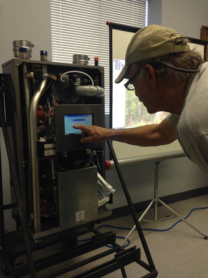 A man is working on a machine and pointing at the screen