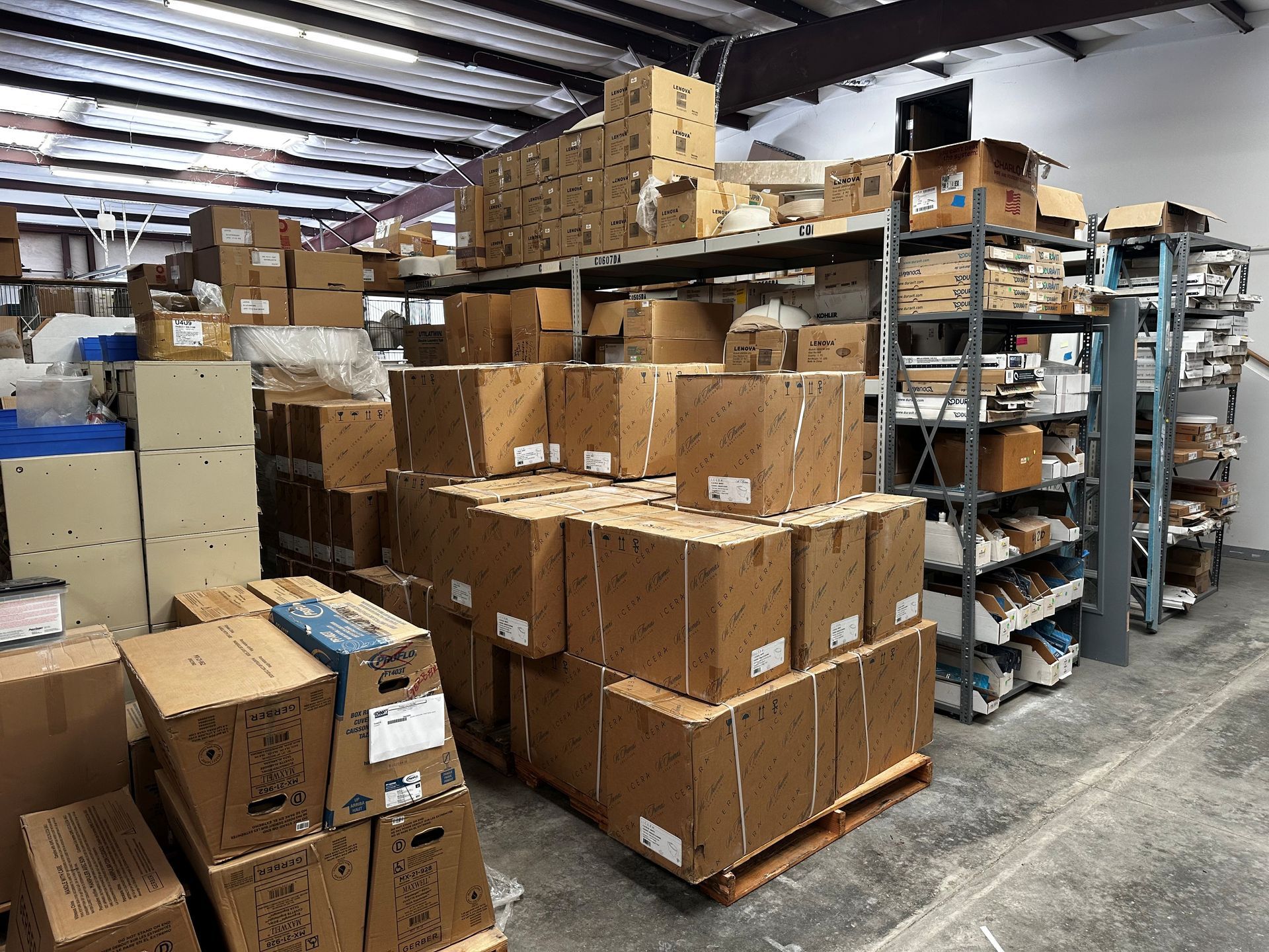 Warehouse interior with numerous cardboard boxes on shelves and pallets.
