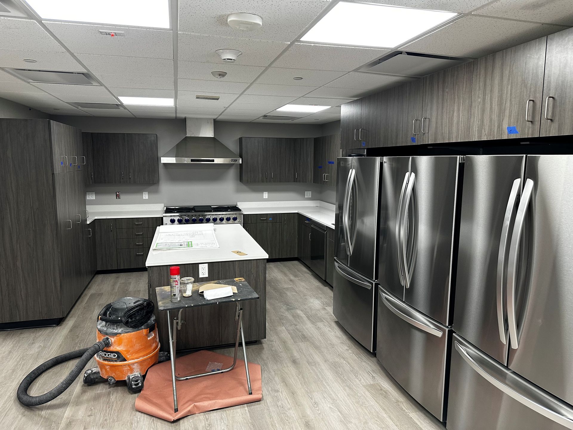 Kitchen under construction with gray cabinets, stainless steel appliances, and an island.
