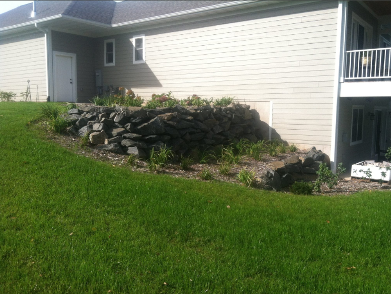 A house with a large rock wall in front of it