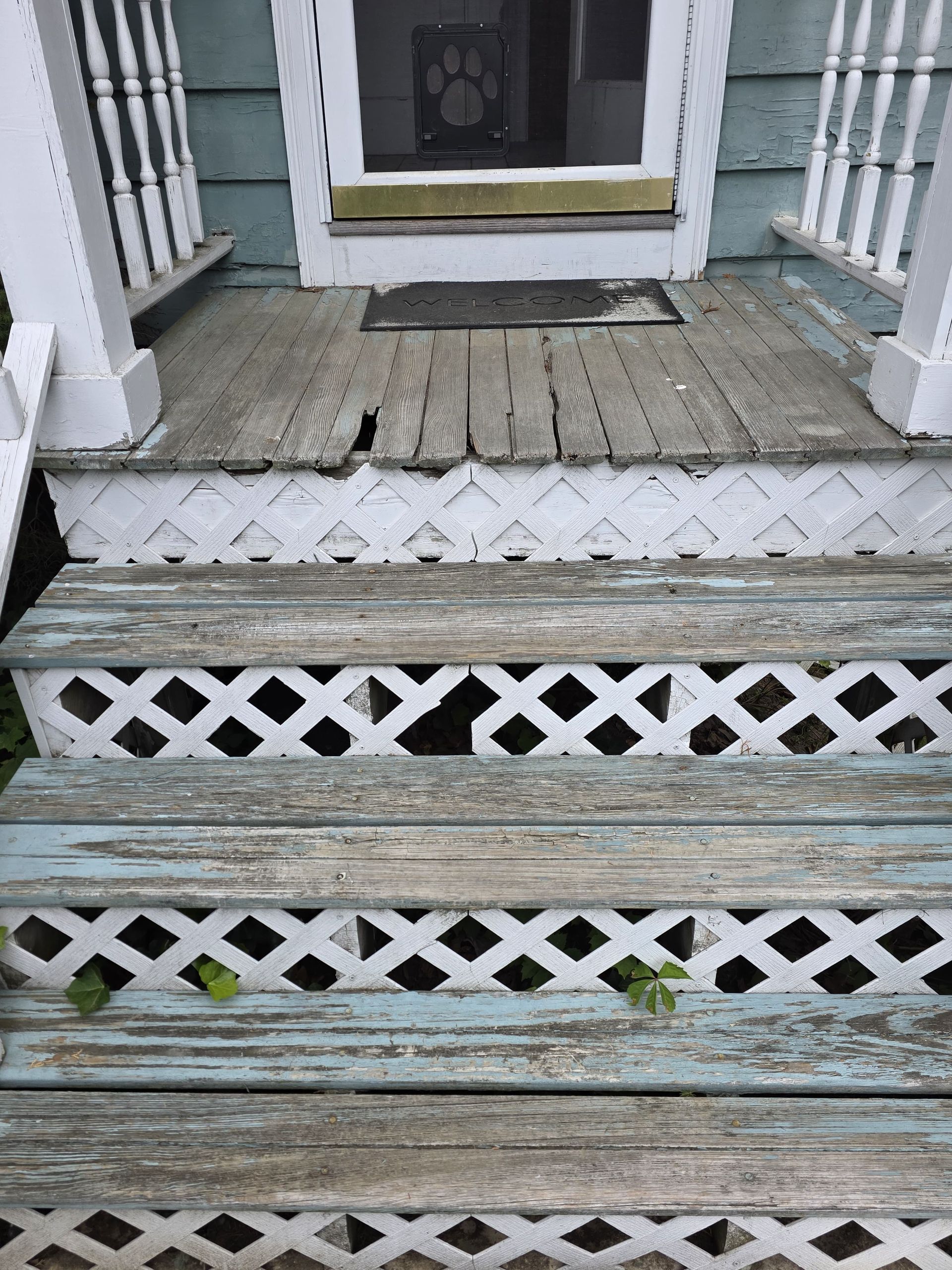 Weathered wooden porch steps with white lattice trim leading to a house entrance