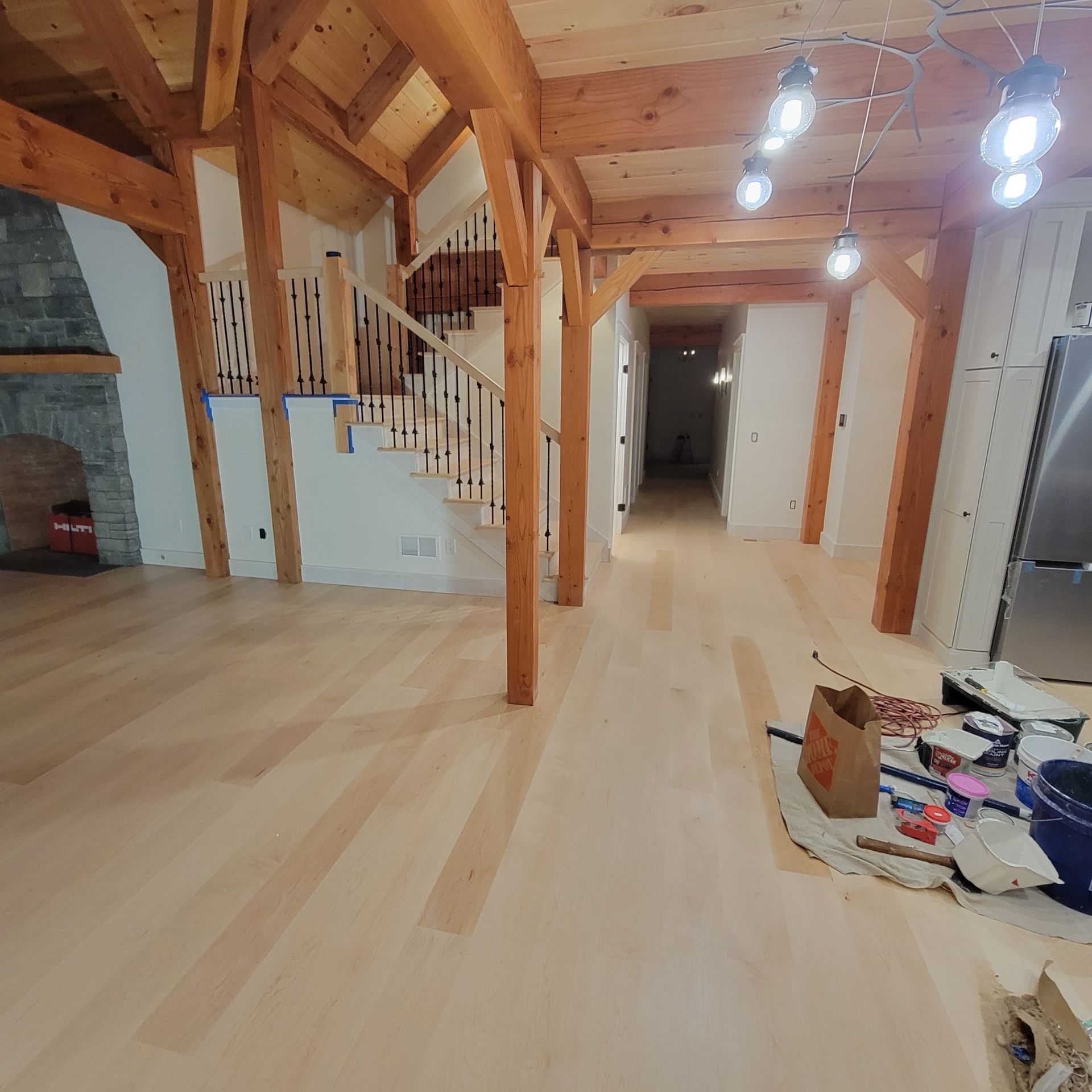 Wooden interior room with exposed beams, staircase, pendant lights, and a long hallway with light hardwood floors