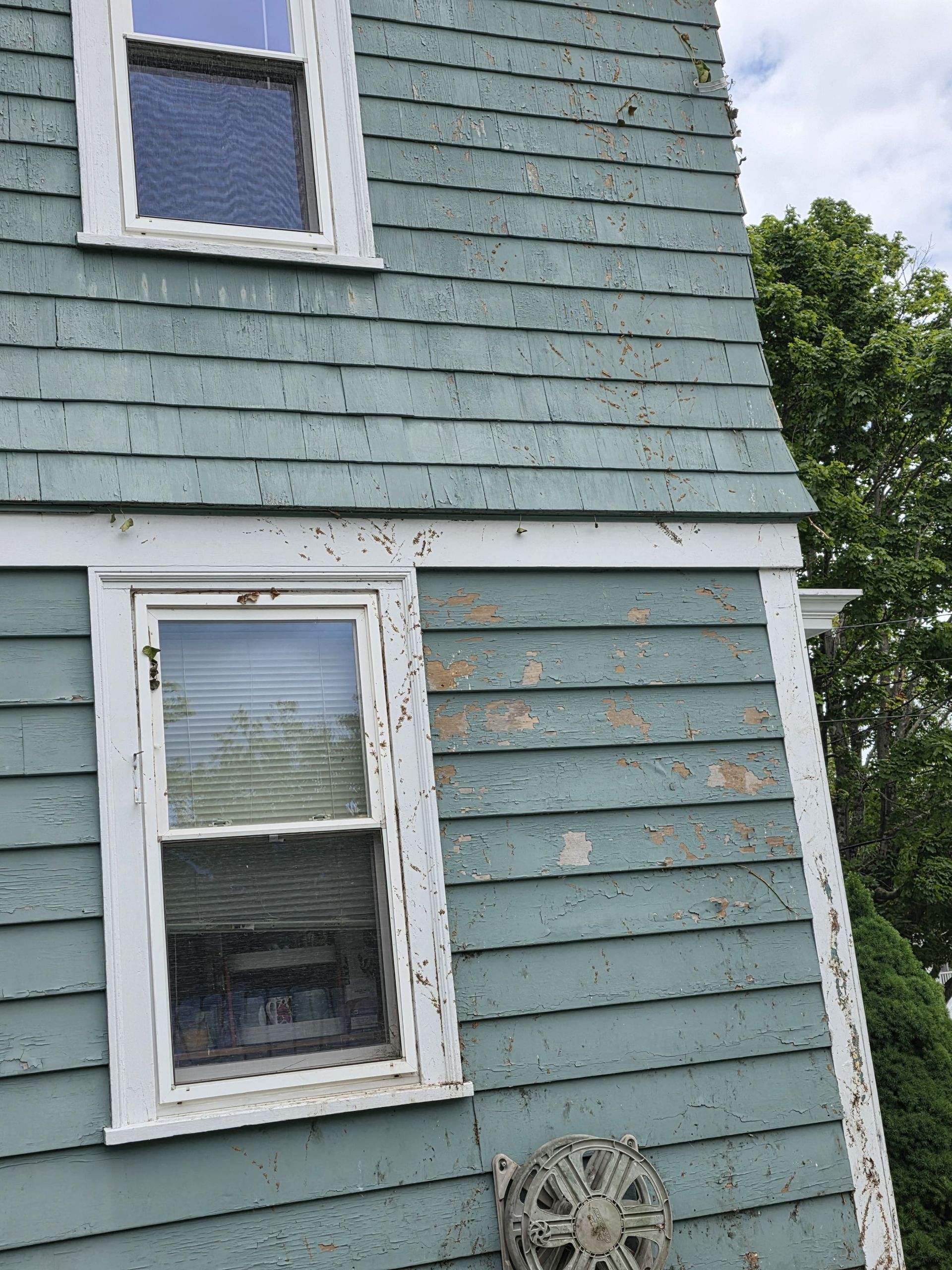 Blue house exterior with white-trimmed windows and weathered siding