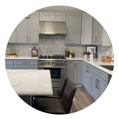 A kitchen with gray cabinets, stainless steel appliances, a stove, and a sink.