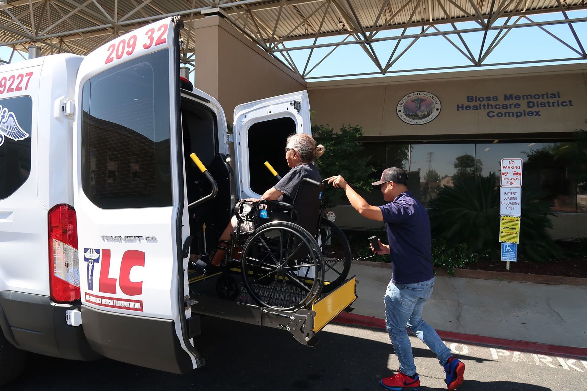 A man is helping a disabled elderly woman in a wheelchair into a van