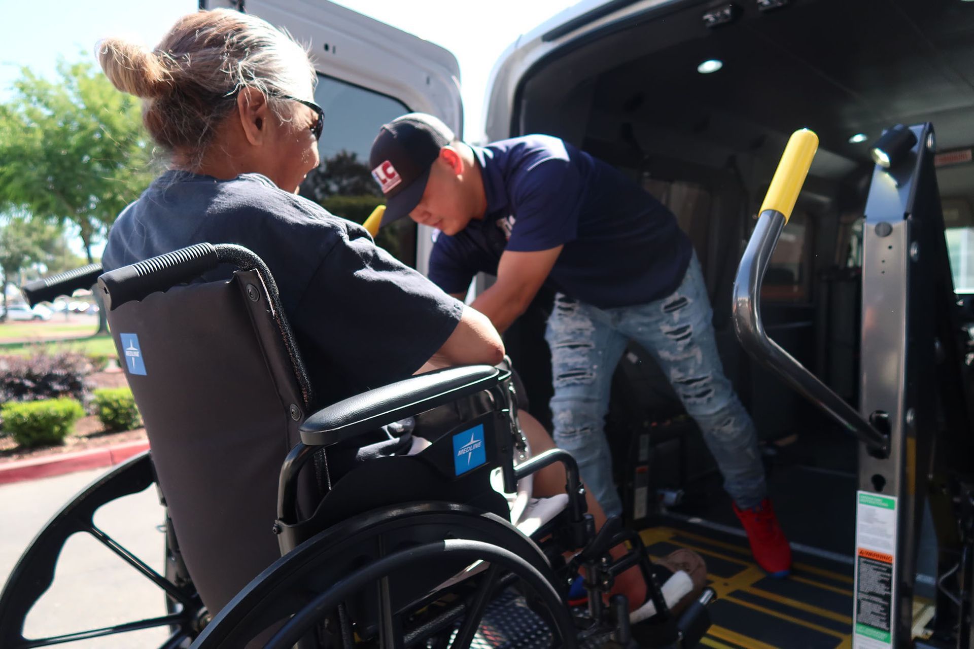 A man is helping a woman in a wheelchair into a van