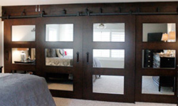 Dark brown sliding doors with glass panels, mounted on a black rail; bedroom interior.
