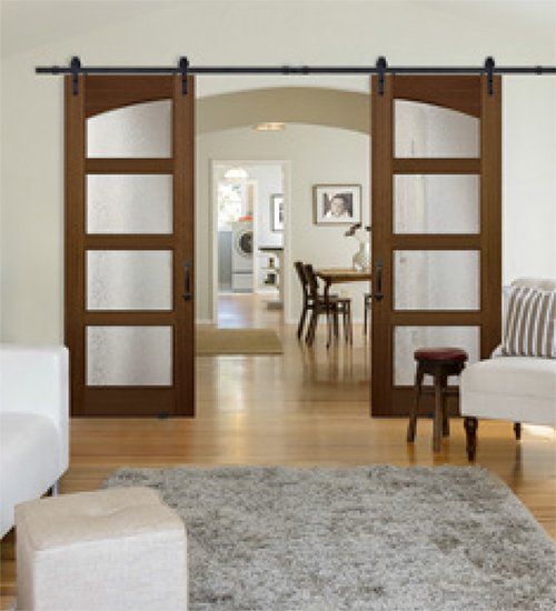 Brown sliding barn doors with glass panels open to a dining room and beyond.