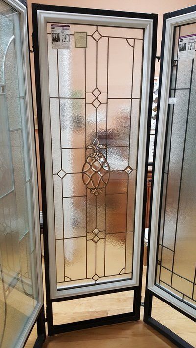 Stained glass window display with black and white frame and floral design, in a showroom.