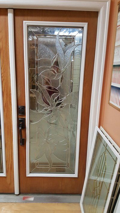 Wooden door with glass panel featuring an etched floral design. White trim surrounds the glass.