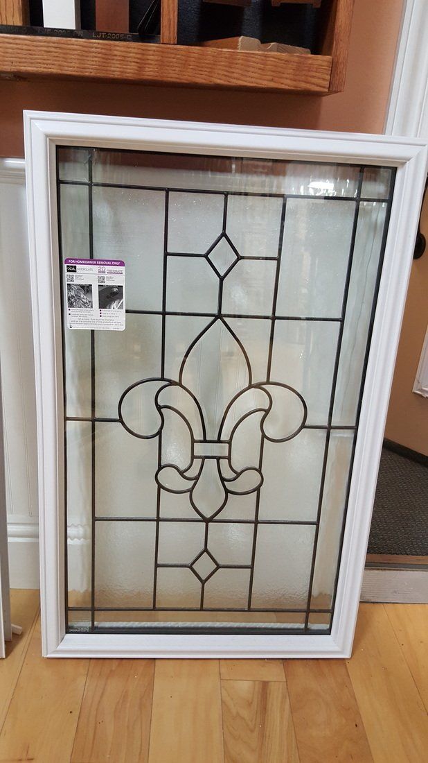 White-framed window with black-lined, stained glass fleur-de-lis design. The window is on display in a store.