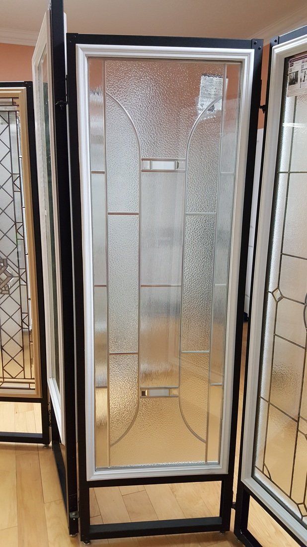 Display of glass door panels with textured and leaded designs, in a showroom setting.