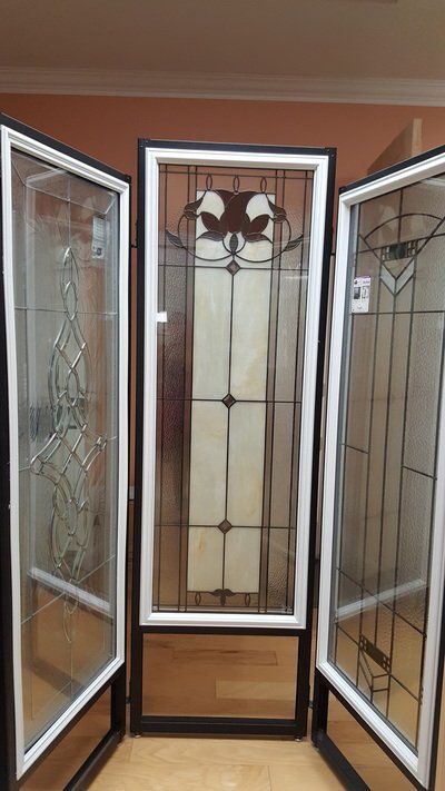Stained glass door panels: center panel features decorative design, flanked by two glass panels, all with black and white frames.