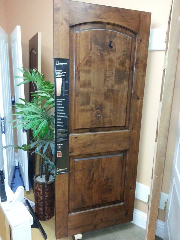 Wooden door with arched top panel, displayed indoors, brown and tan tones.