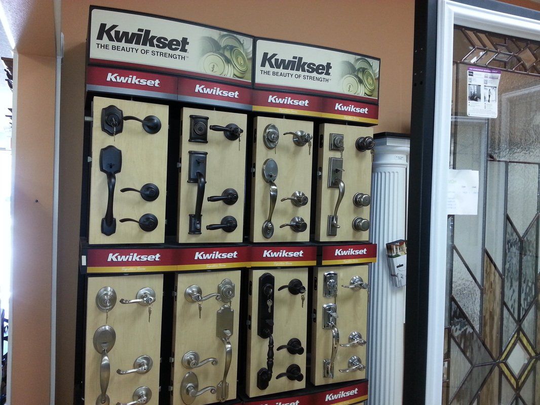 Display of Kwikset door hardware in a store. Handles and locks in various styles are shown on wooden boards.