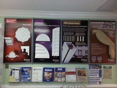 Display of architectural product samples and brochures on a wall; includes decorative molding and columns.