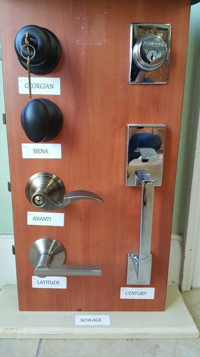 Door lock samples on a brown wooden board with white labels.