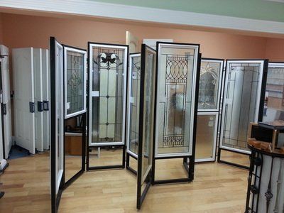 Display of glass-paneled doors in a showroom, each framed in black and white, various designs.