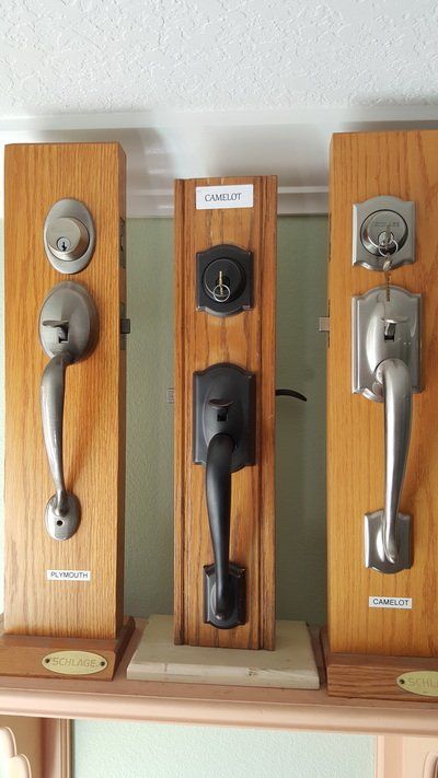Three door handle sets displayed on wooden boards for sale.