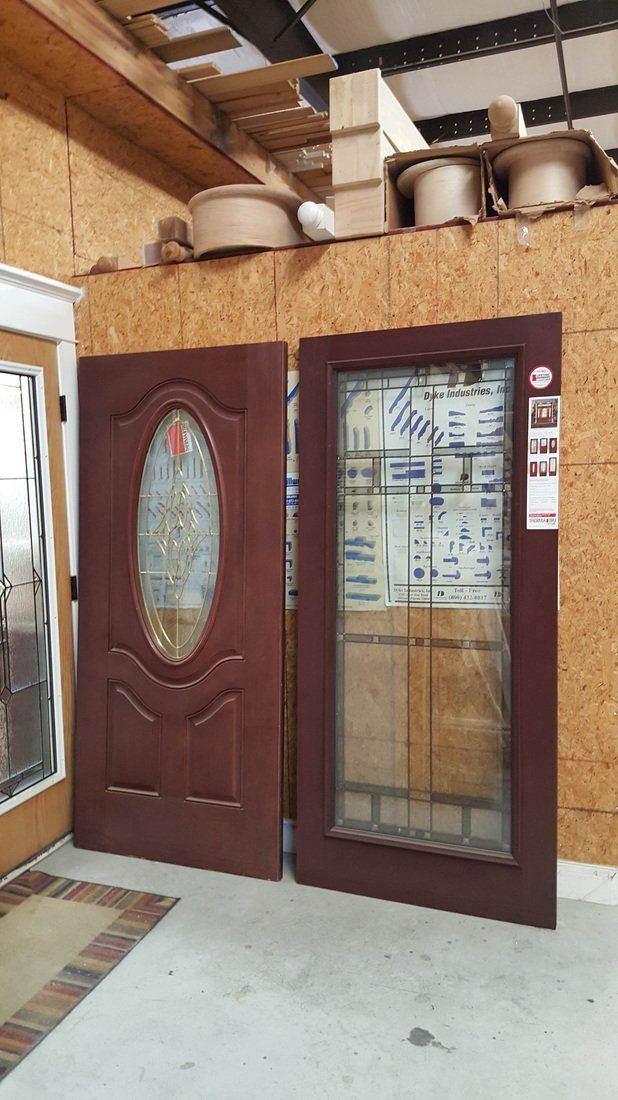 Two red-brown exterior doors with glass panels against a wood-paneled wall inside a store.