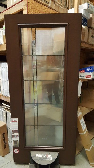 Brown front door with glass panel and decorative lines, inside a store.