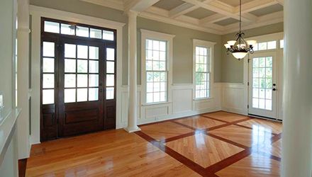 Elegant entryway with dark wood door, windows, and patterned hardwood floor.