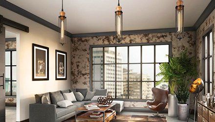 Living room with exposed brick wall, large window, gray sectional sofa, and industrial-style pendant lights.