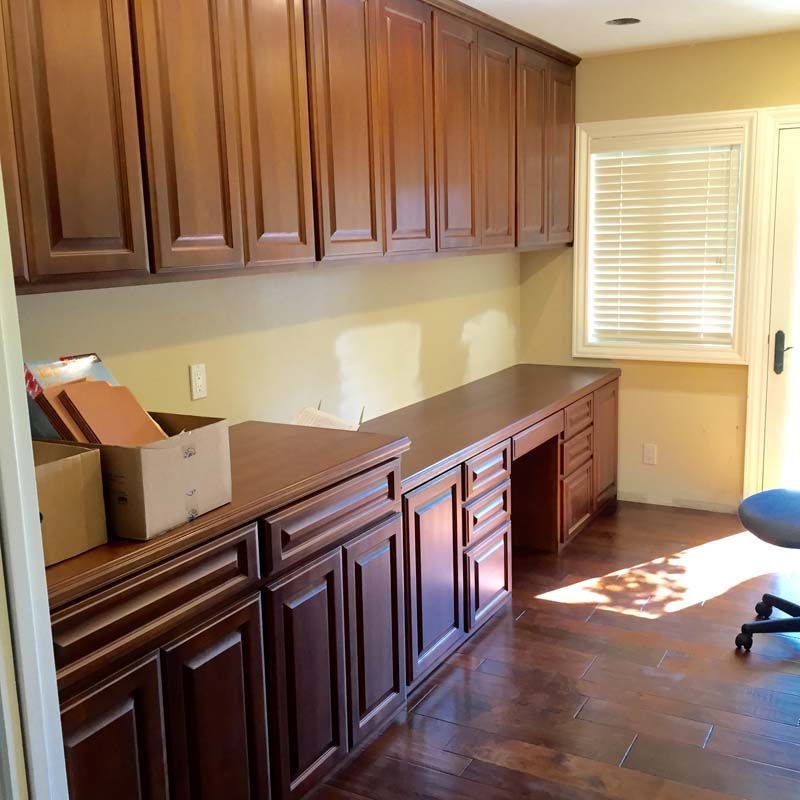 Office with brown cabinets and desk, hardwood floors, and a window with blinds.