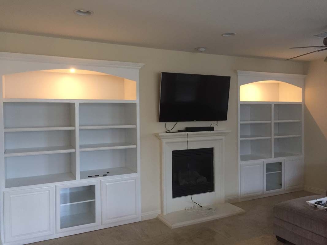 White built-in bookshelves frame a fireplace with a mounted TV.