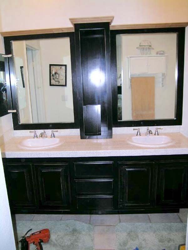 Black bathroom vanity with two mirrors, sinks, and storage cabinets.