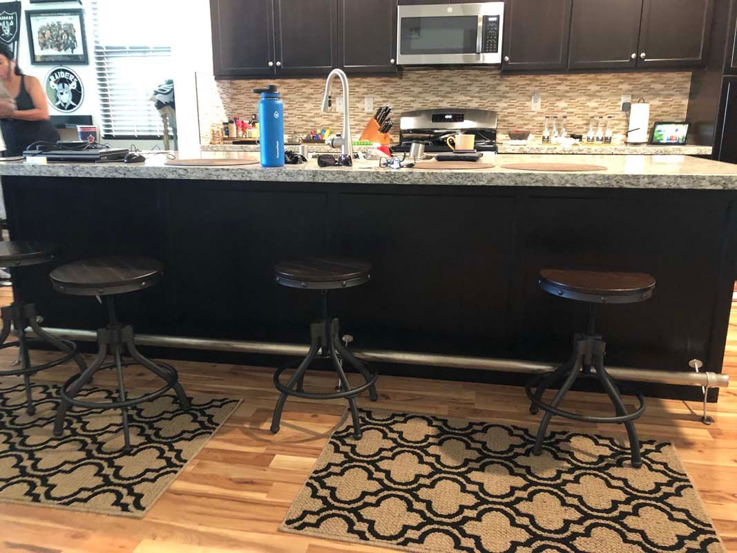 Kitchen island with three stools, a person, and countertop appliances.