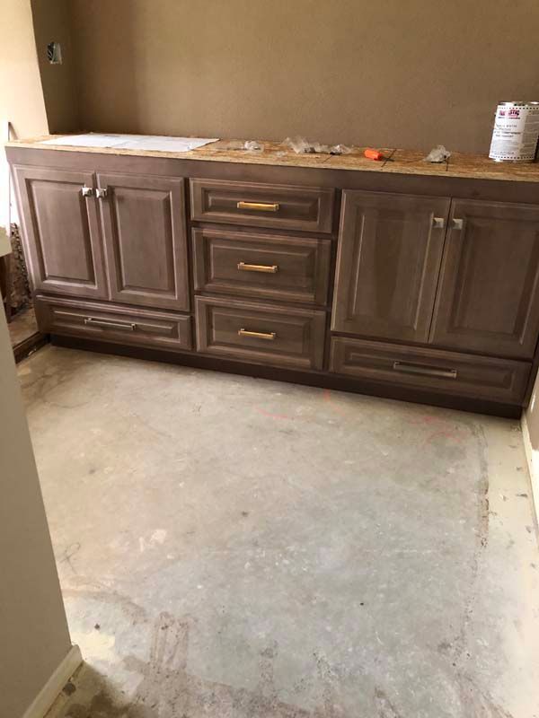 Brown bathroom vanity with gold handles, unfinished walls and floor.