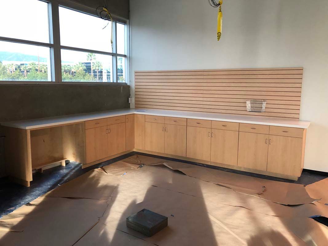 A light wood cabinet set in a corner next to a window, with a textured wood backsplash.